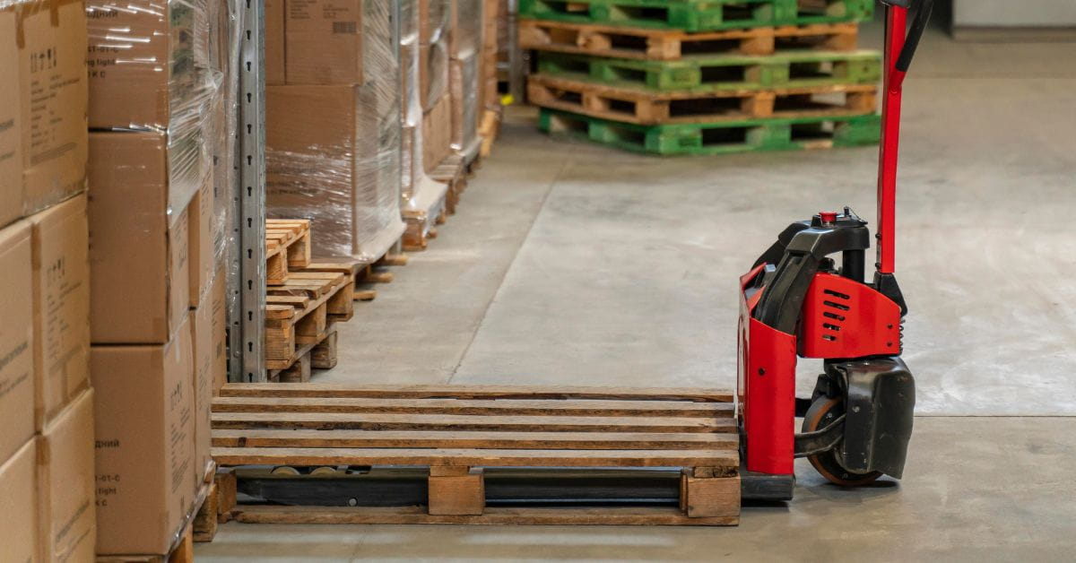 A red handlift handling a wooden pallet in a warehouse