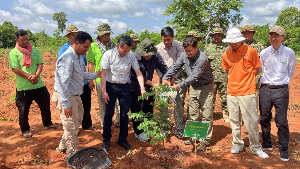 a group of men watering a tree together